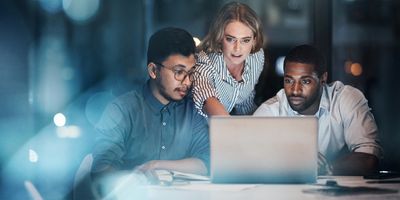 Three workers looking at a laptop discussing a project