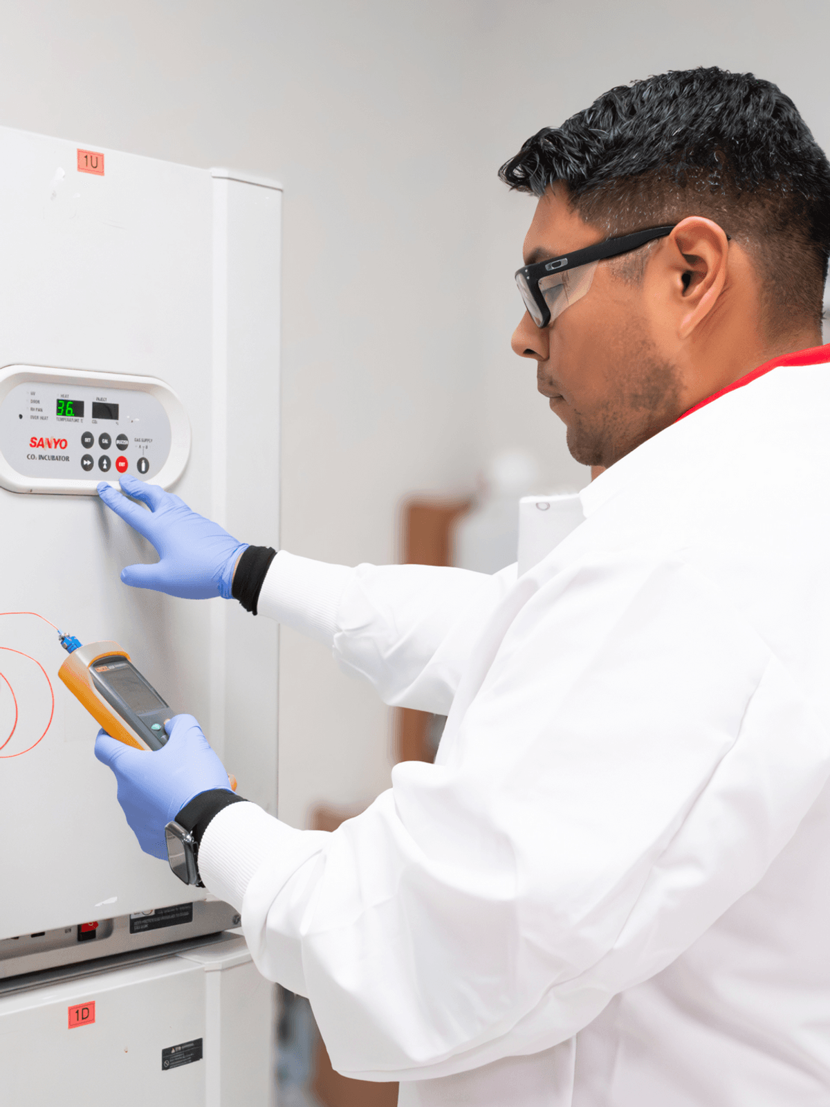 A lab technician pushes buttons on a lab incubator A lab technician pushes buttons on a lab incubator